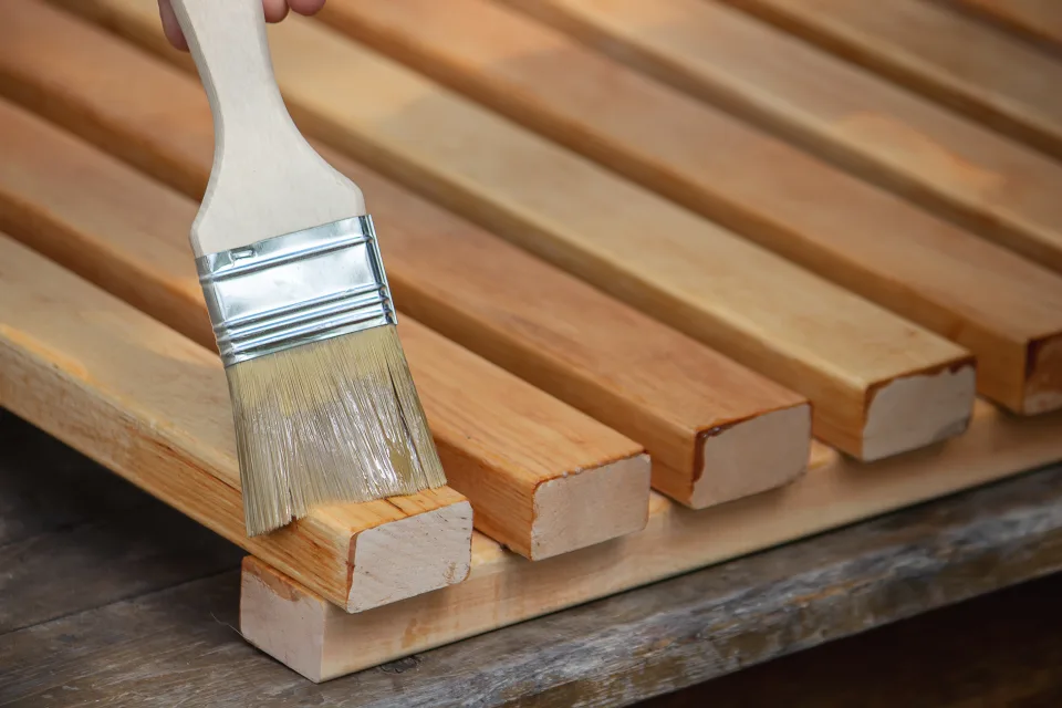 Patio trasero con cerca de madera teñida en tono marrón junto a la fachada lateral blanca de la casa
